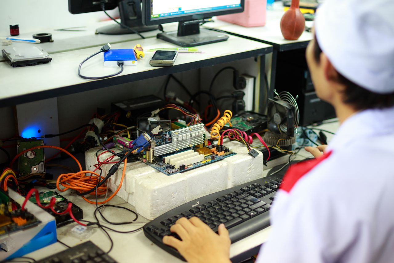our-value A man in a laboratory uniform working on computer components and wiring at a workstation.