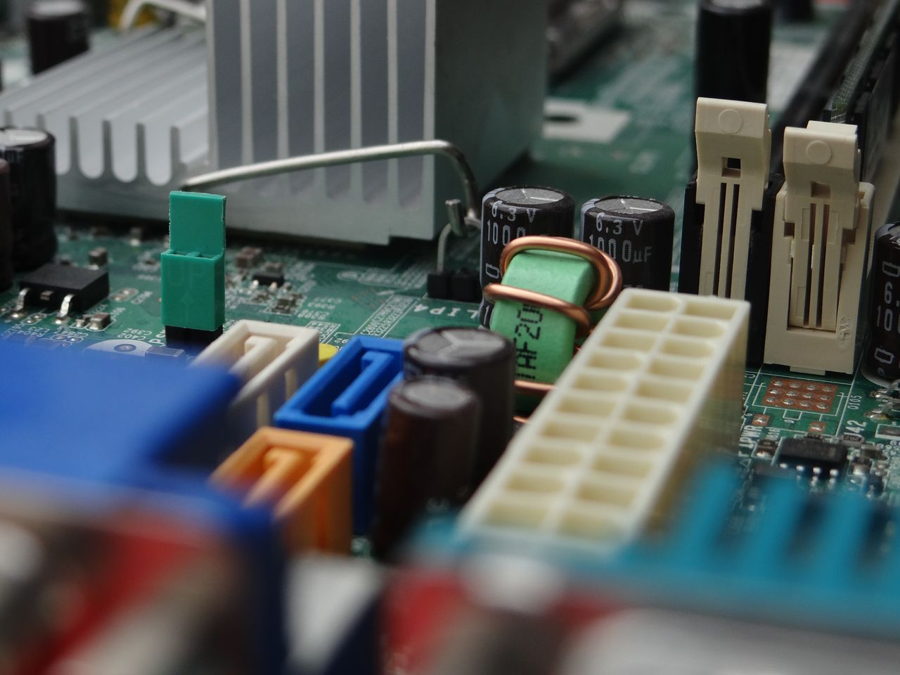 our-mission Detailed view of electronic components on a computer motherboard focusing on connectors and capacitors.